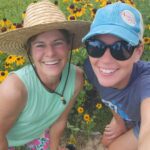 women in front of black eyed susan flowers